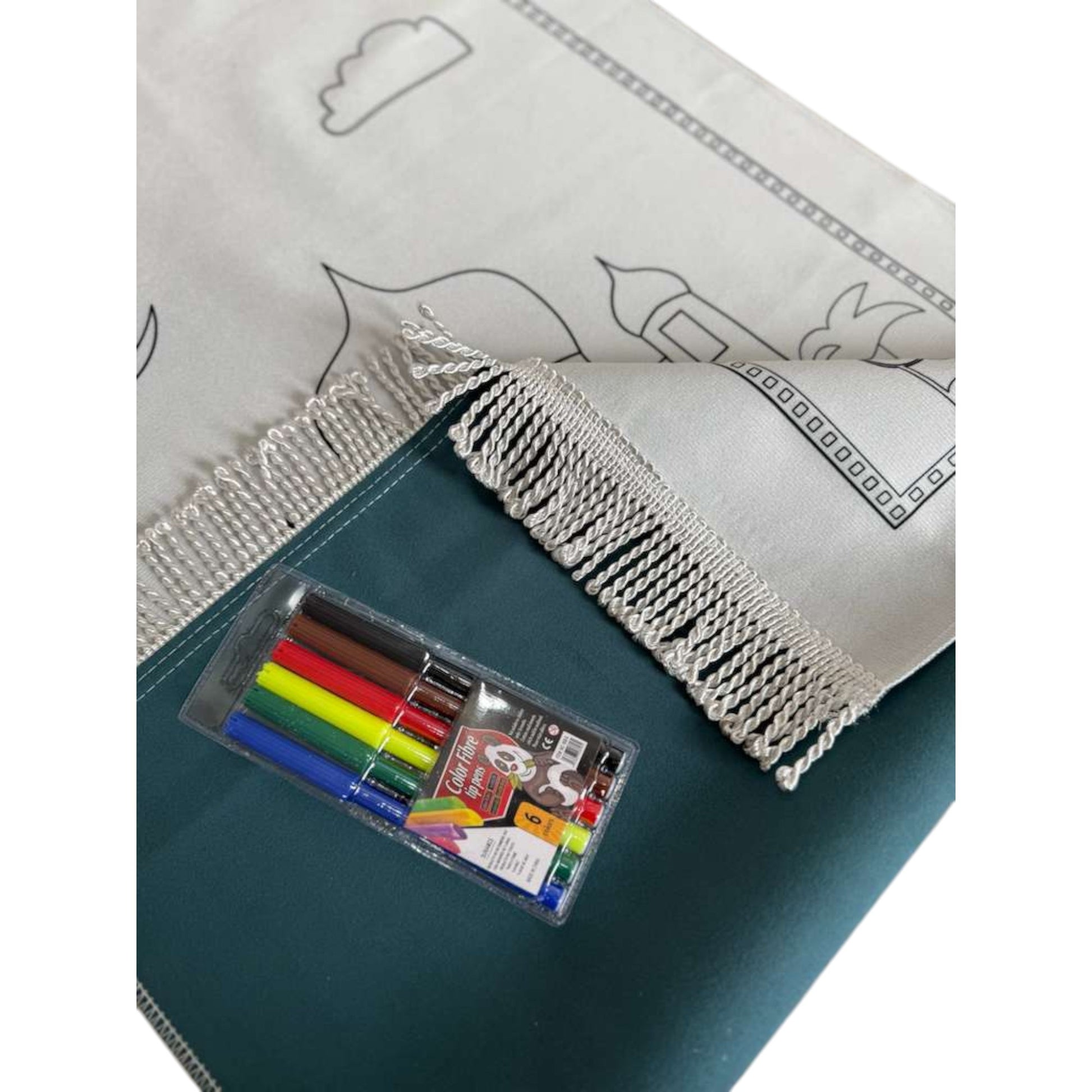 Coloring book with markers and a white cover featuring black line art on a green surface.